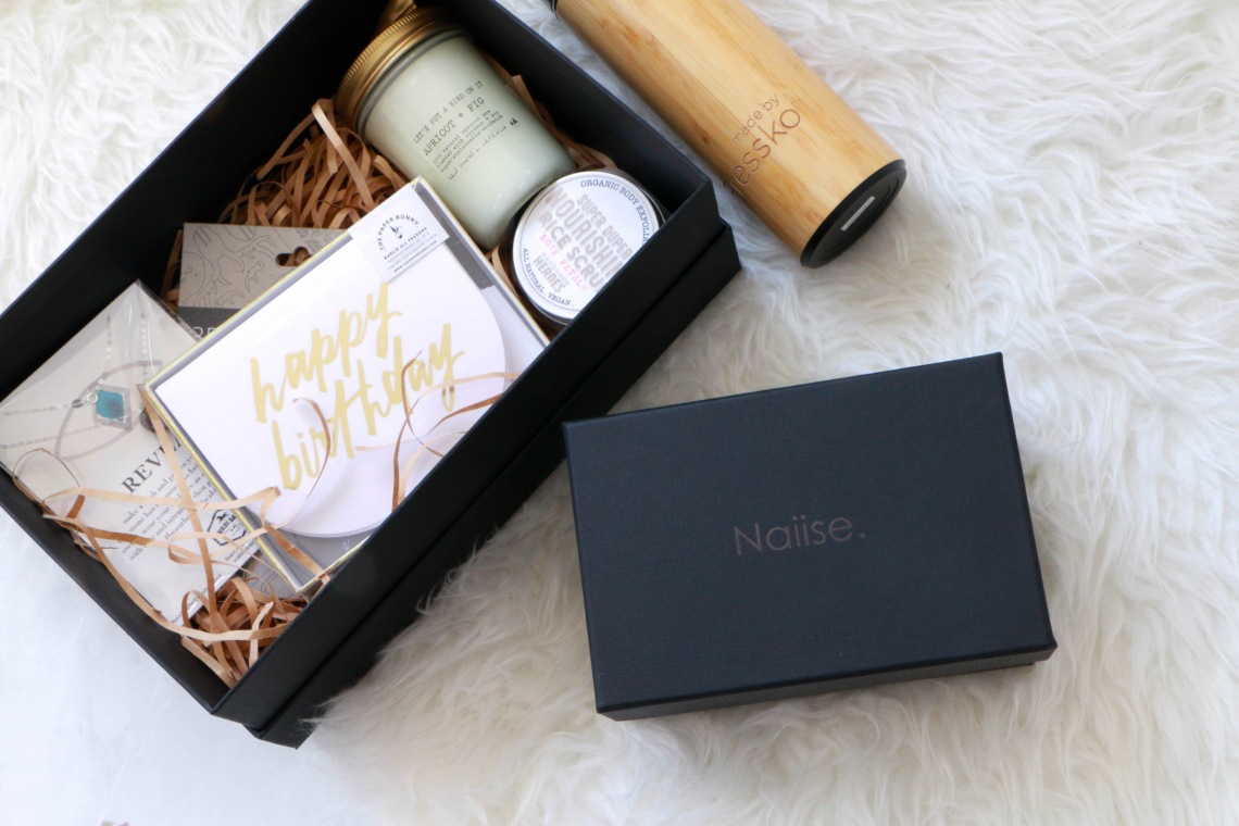 A gift box of a postcard, necklace and skincare products from Naiise